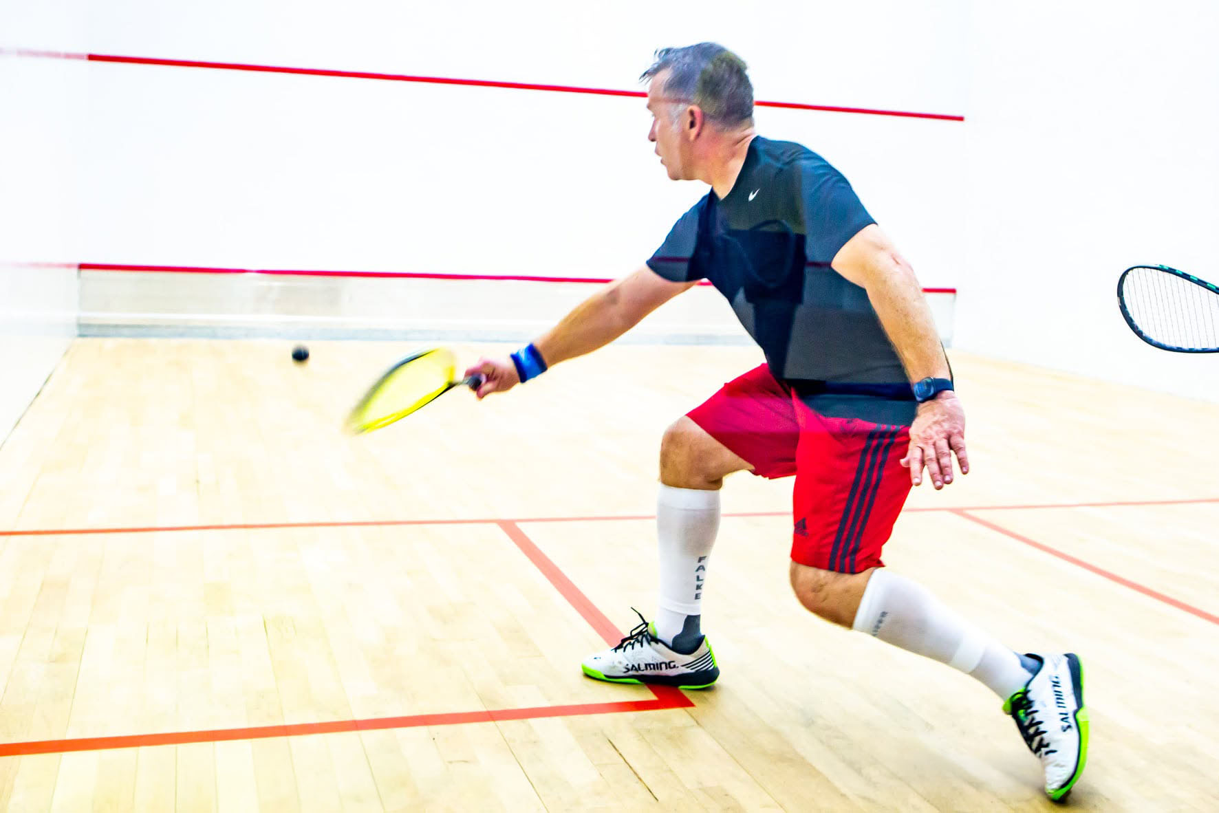 Squash player lunging on court
