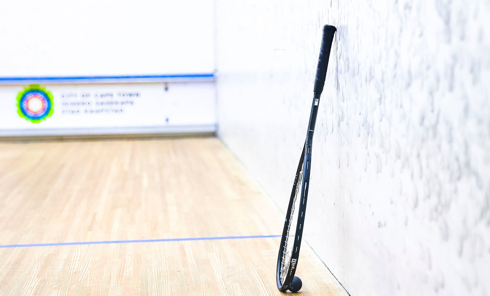 Squash racquet resting against a court wall